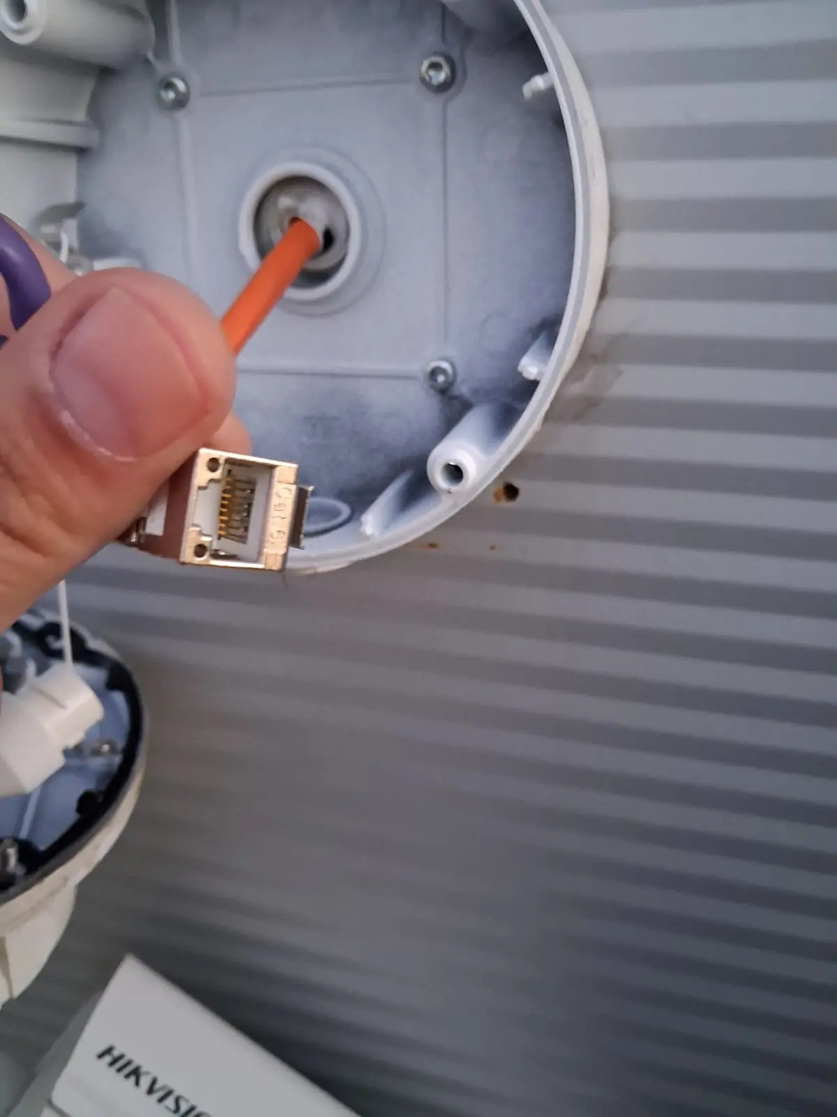 Cat6-Patchkabel mit RJ45-Stecker wird in die Anschlussdose einer Hikvision-PoE-Außenkamera geführt