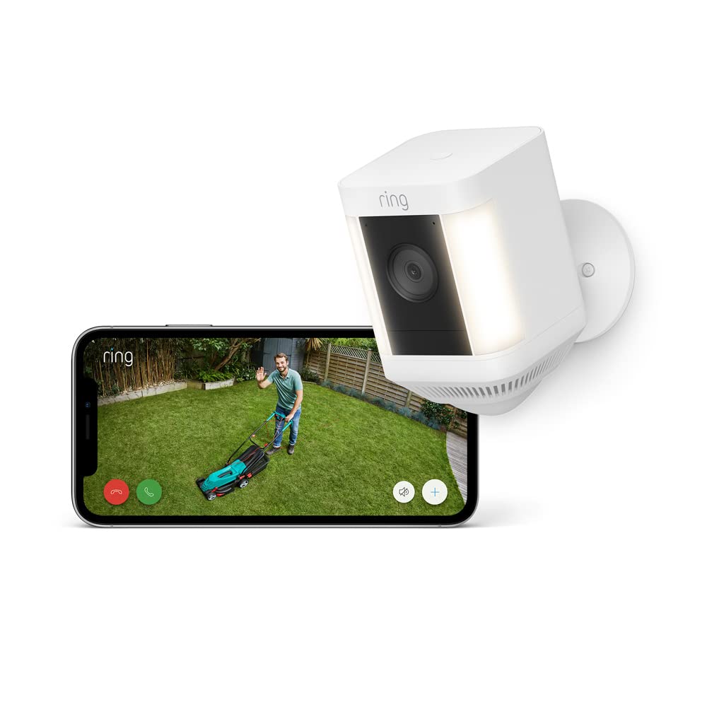 Ring Spotlight Cam Plus mit hellen LED-Spotlights an der Fassade – Live-Ansicht auf dem Smartphone eines Mannes mit Rasenmäher im Garten