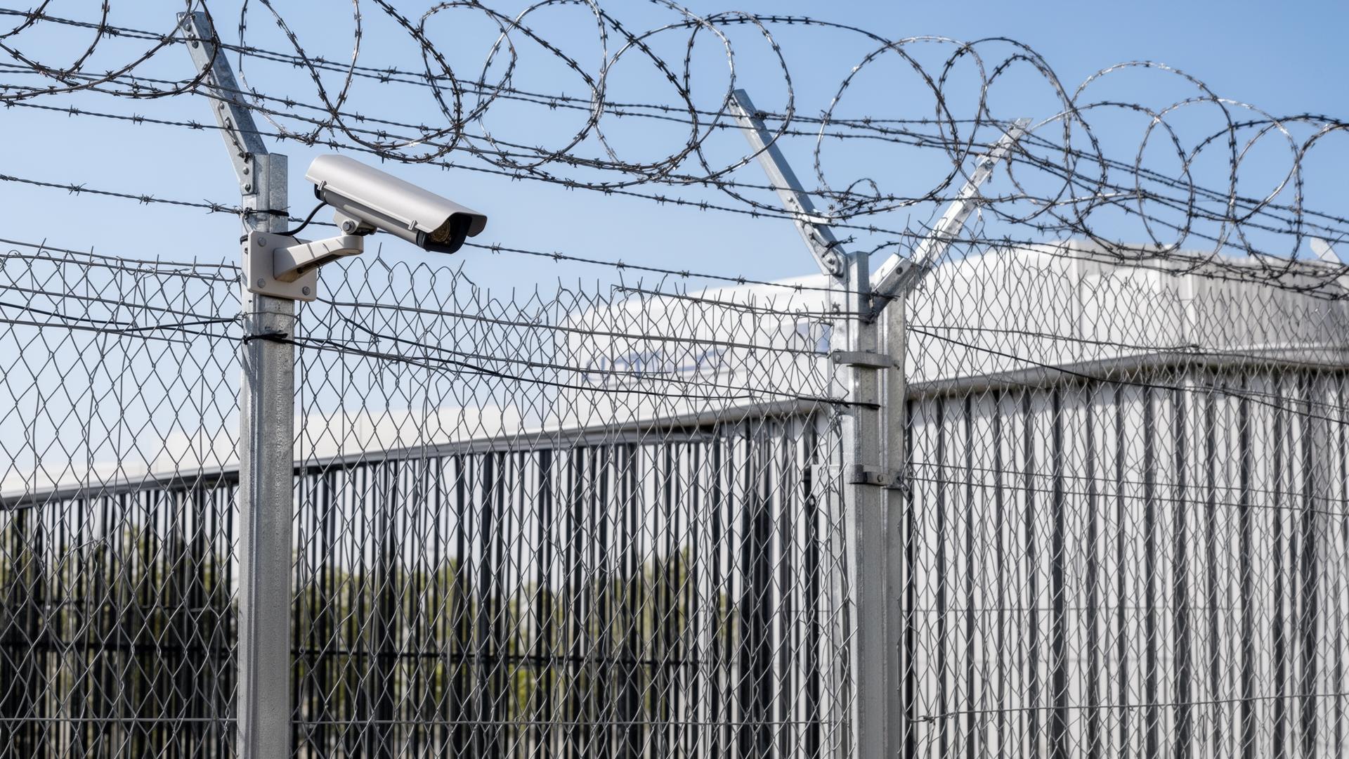Industriezaun mit Stacheldraht und Überwachungskamera am Firmengelände
