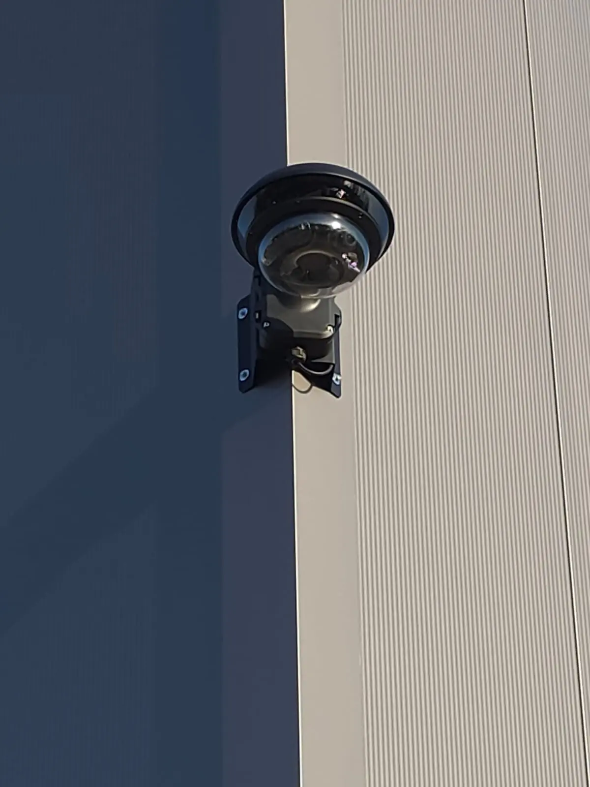 Multisensor-Panoramakamera mit mehreren Linsen unter einem schwarzen Schutzdach an der Fassade eines Mehrfamilienhauses – ideal für 180°-Überwachung von Eingangsbereich und Hof