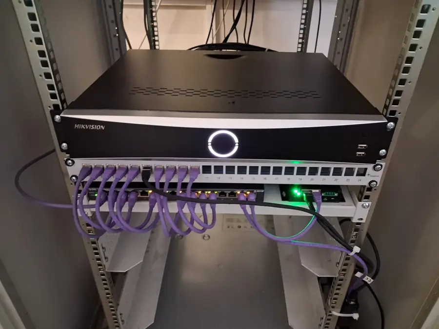 Hikvision NVR mit Patchpanel und PoE-Switch im Netzwerkschrank für Überwachungskameras