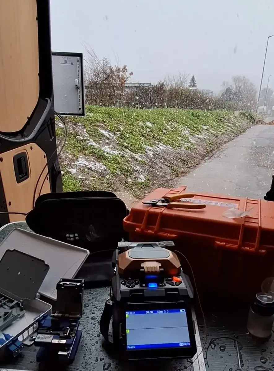 Glasfaser-Spleißeinsatz im Schnee: Fusion Splicer, Cleaver und Werkzeugkoffer im offenen Servicebus eines CCTV-Technikers
