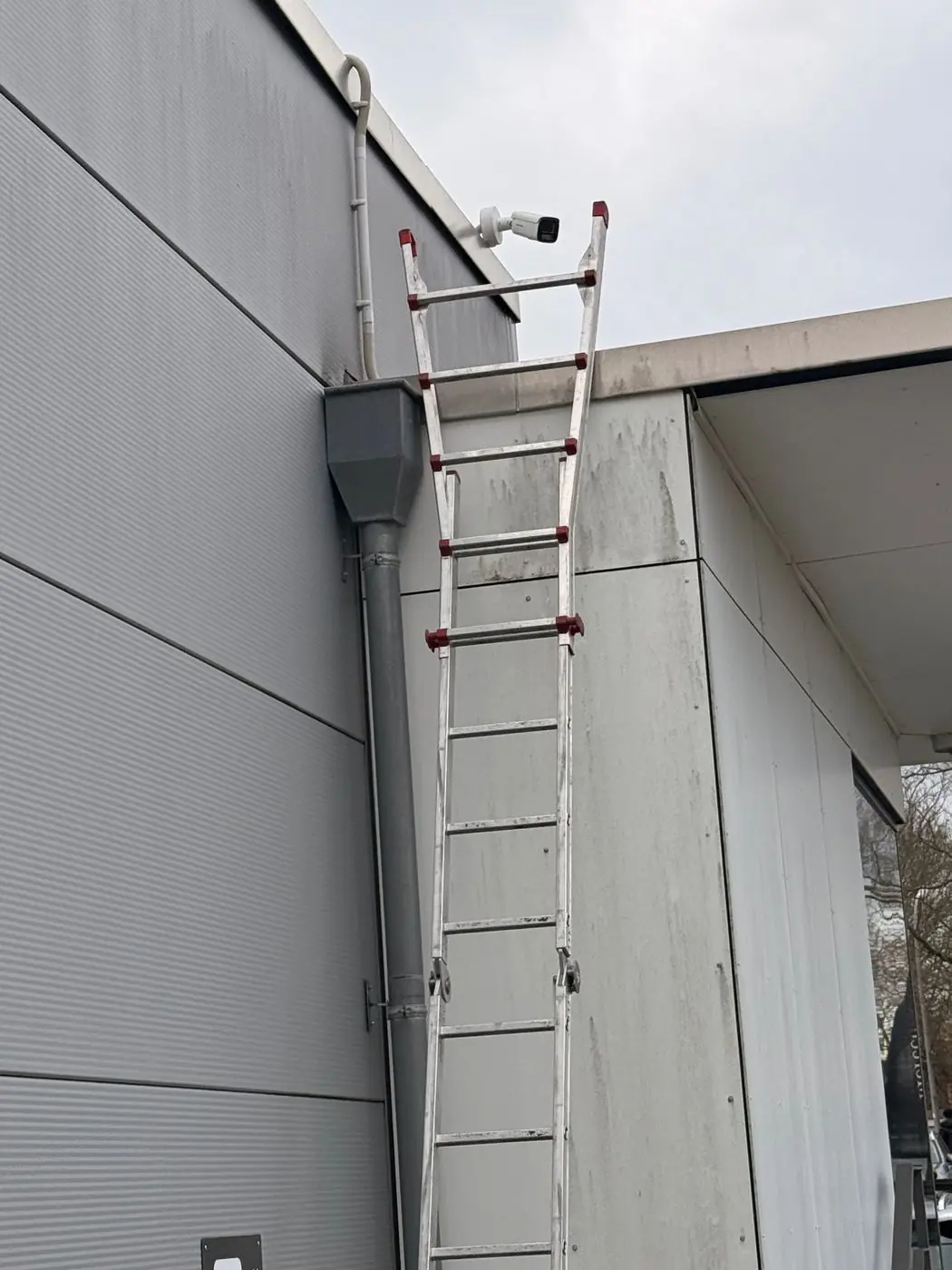 Hikvision IP-Bulletkamera unter dem Dach eines Gewerbeobjekts, Installation per Leiter