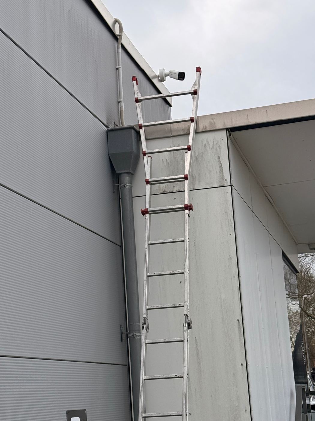 Hikvision IP-Bulletkamera unter dem Dach eines Gewerbeobjekts, Installation per Leiter