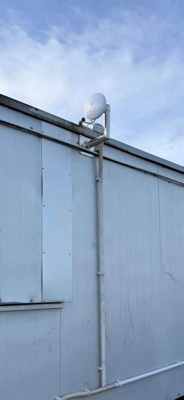 Ubiquiti NanoBeam Richtfunkantenne auf einem Flachdach montiert – Punkt-zu-Punkt-Verbindung zwischen zwei Gebäuden